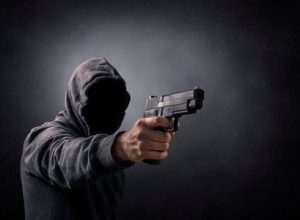 153036132-homem-com-capuz-com-uma-arma-no-escuro